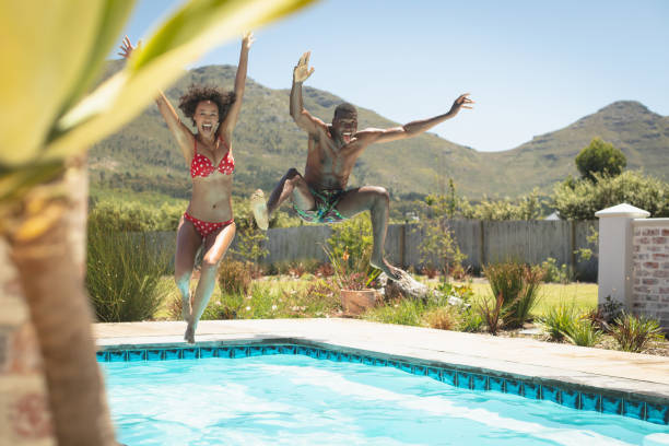 heureux jeune couple afro-américain sautant dans une piscine dans leur cour arrière - male beauty beauty hairstyle shirtless photos et images de collection