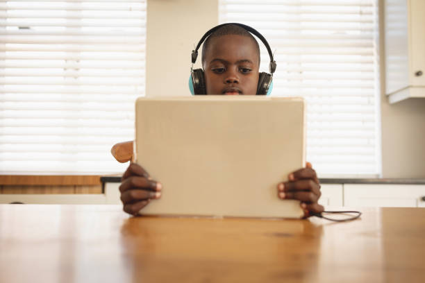 istock African American boy playing game on digital tablet at dining table in kitchen 1129673739