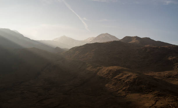 Mountain range with sunbeams Sunbeams sweeping across snowdonia mountains. llyn gwynant stock pictures, royalty-free photos & images
