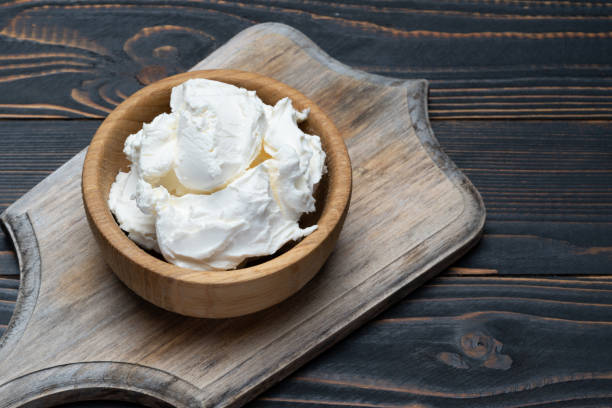 istock Traditional Mascarpone cheese in wooden bowl on table 1129676475