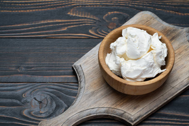 istock Traditional Mascarpone cheese in wooden bowl on table 1129676476