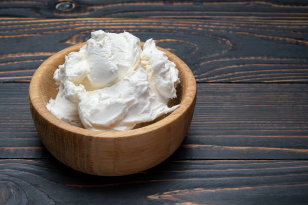 istock Traditional Mascarpone cheese in wooden bowl on table 1129676480