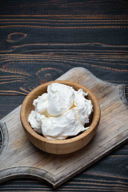 istock Traditional Mascarpone cheese in wooden bowl on table 1129676482