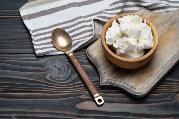 istock Traditional Mascarpone cheese in wooden bowl on table 1129676489