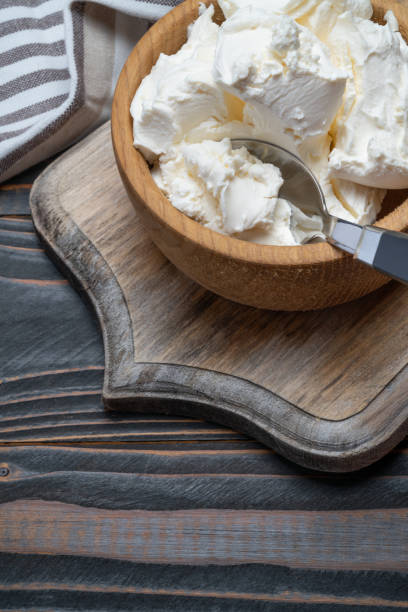 istock Traditional Mascarpone cheese in wooden bowl on table 1129676495