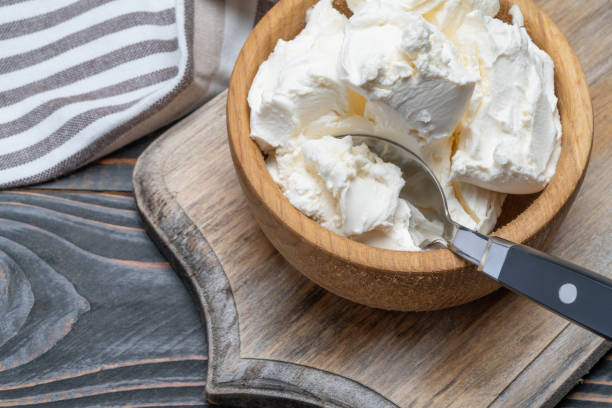 istock Traditional Mascarpone cheese in wooden bowl on table 1129676508