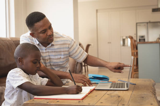 istock African American father helping his son with homework on laptop at table 1129676666