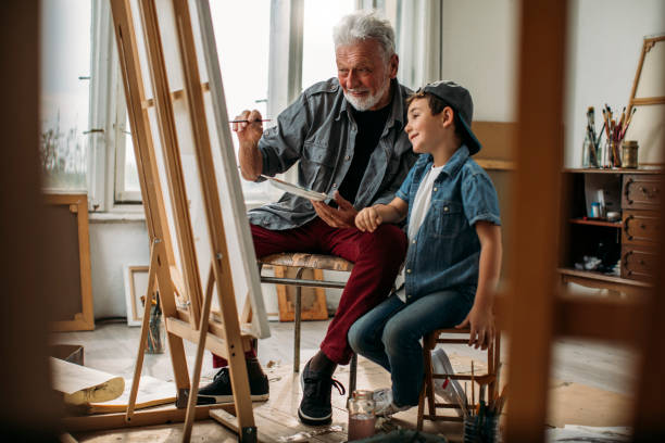 istock Schoolboy painting with grandpa 1129676675