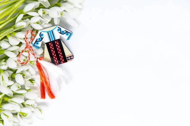 snow drops and pendant known as martisor on white with copy space, balkanic symbol of spring offered to loved ones as a talisman of good luck, health, friendship, love and respect