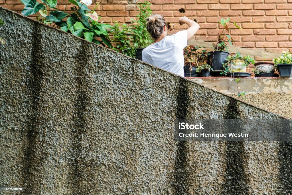 Young blond woman in her 30s taking care of the garden Home Interior Stock Photo