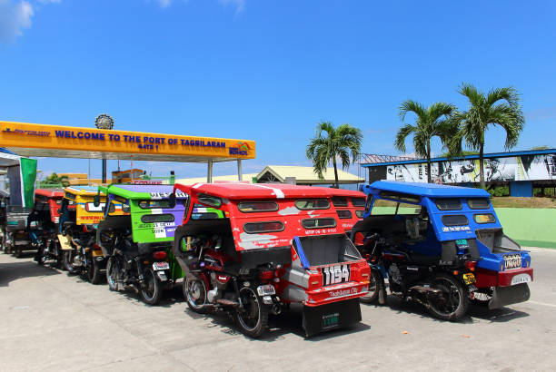 Tricycle motorbike taxi near gate sea port in Bohol Island Tagbilaran, Philippines - September 30, 2018: Parking motorized tricycles taxi awaiting passengers or tourists near gate to the port of Tagbilaran in Philippines, Bohol Island. Selective focus philippines tricycle stock pictures, royalty-free photos & images