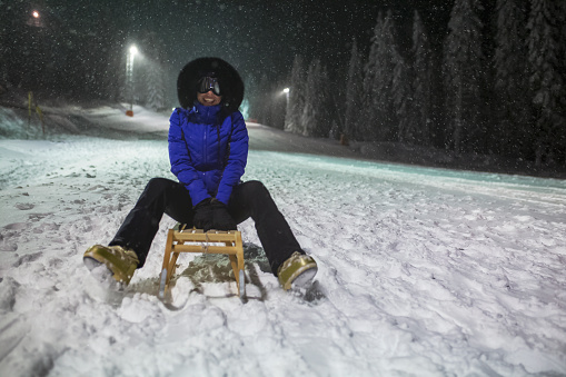 Woman tobogganing at ski resort at night