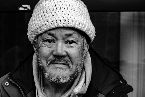 A black and white image of a homeless Asian American man on the Portland, Oregon streets during the winter.
