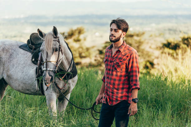 istock Man and his horse walking on the grass 1129687692