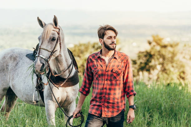 istock Man and his horse walking on the grass 1129687715