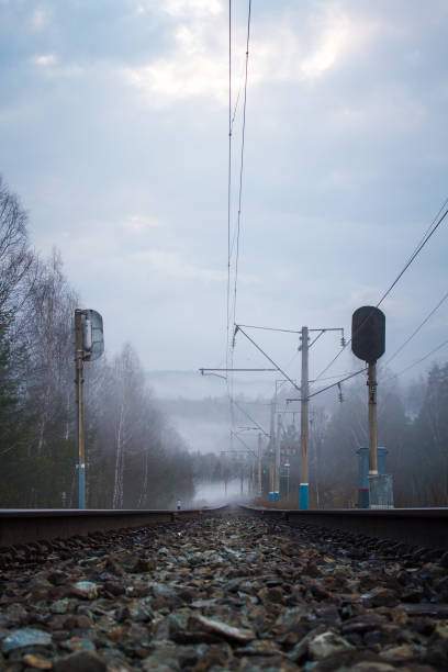 istock railway tracks, traffic light and electric poles in fog 1129688043