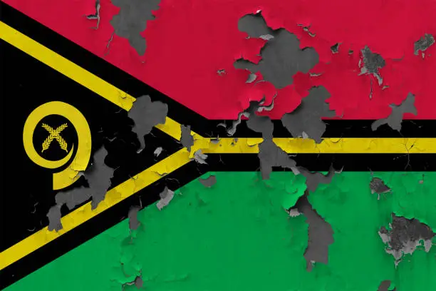 Photo of Close up grungy, damaged and weathered Vanuatu flag on wall peeling off paint to see inside surface.