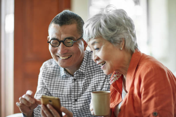istock Smiling senior couple using mobile phone at home 1129693307