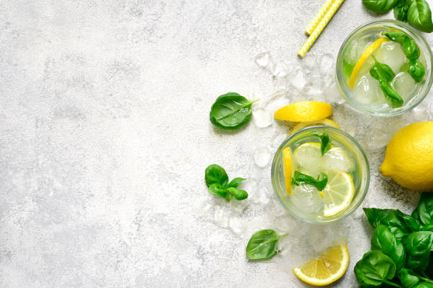 Homemade summer basil lemonade Homemade summer basil lemonade in a glasses over light slate, stone or concrete background.Top view with copy space. carbonated photos stock pictures, royalty-free photos & images