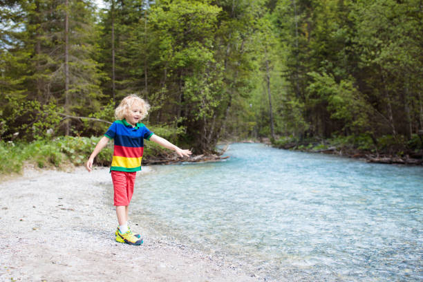 istock Child hiking in mountains. Kids at river shore. 1129693907