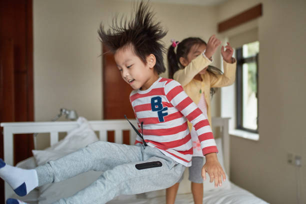 istock Playful brother and sister jumping on bed 1129695424