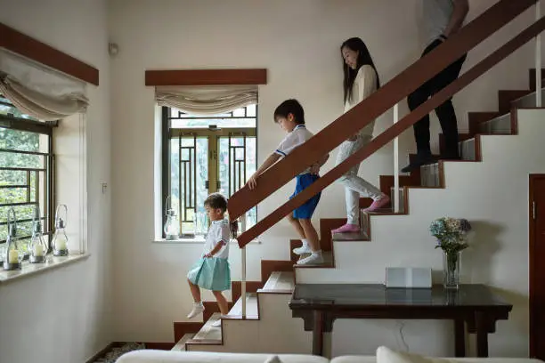 Photo of Side view of family walking down steps at home