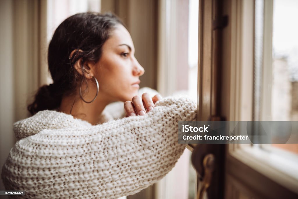 pensive woman in front of the window Women Stock Photo