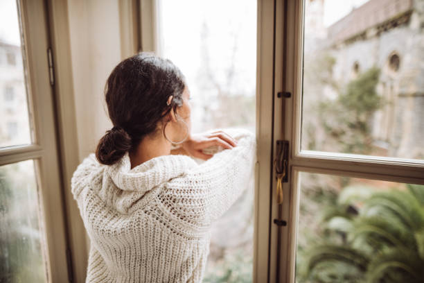istock pensive woman in front of the window 1129696790