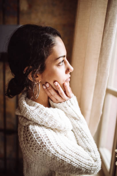 istock pensive woman in front of the window 1129696812