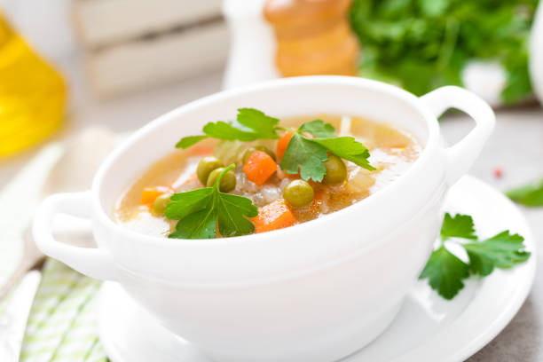 istock Summer light vegetarian vegetable soup with carrot, potato, cabbage and grean peas on white background. Diet healthy and tasty lunch. Baby food 1129701219