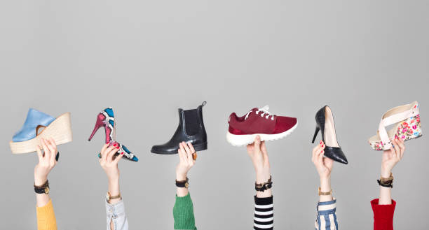 istock Hands holding different shoes on gray background 1129702431
