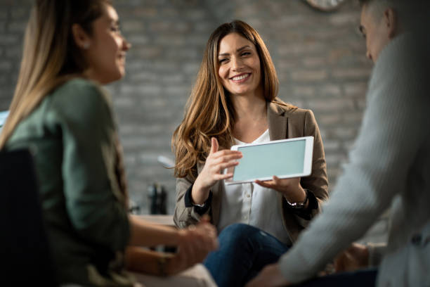 istock Happy bank manager using touchpad while having a meeting with clients in the office. 1129703881