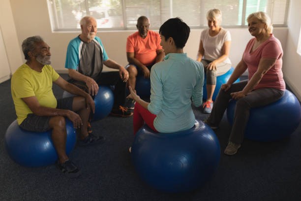 istock Female trainer training senior people in performing exercise 1129704363