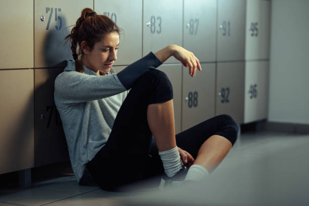 donna atletica pensierosa seduta sul pavimento nello spogliatoio. - dressing room women female adult foto e immagini stock
