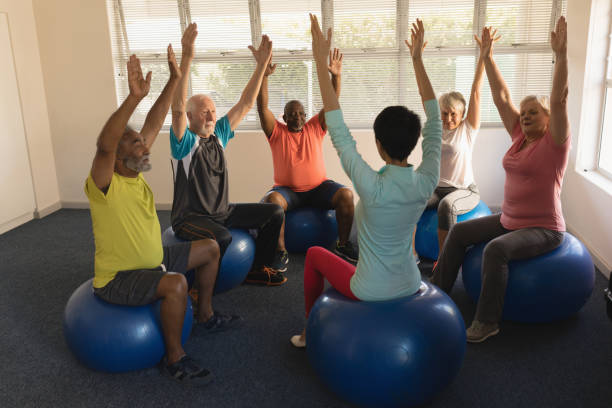 Female trainer training senior people in performing exercise