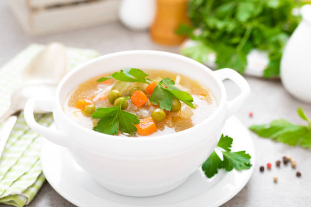 istock Summer light vegetarian vegetable soup with carrot, potato, cabbage and grean peas on white background. Diet healthy and tasty lunch. Baby food 1129705453