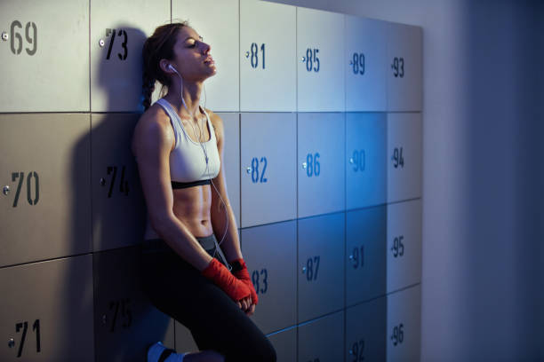 escuchar música de deportista sudorosos en audífonos en vestuario. - boxing womens fotografías e imágenes de stock