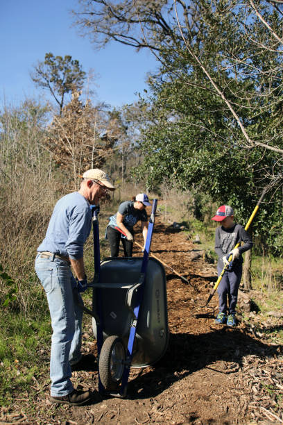 MLK Holiday Day of Service, Pease Park, Austin, Texas Austin, Tx, USA - Jan. 21, 2019:  A mother and son volunteer team spreads mulch on a trail in Pease Park while participating in the Martin Luther King Holiday Day of Service. martin luther king jr day stock pictures, royalty-free photos & images