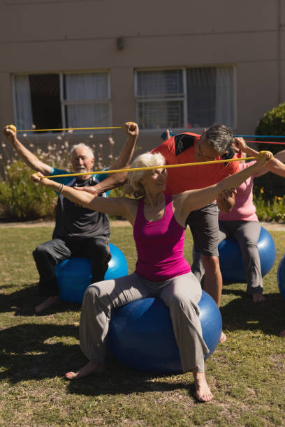 istock Trainer assisting senior women in performing exercise 1129710616