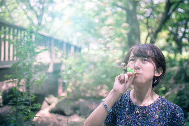 Young woman blowing bubbles in forest