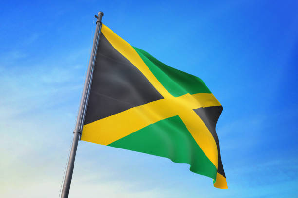istock Jamaica flag waving in the blue sky 1129718525