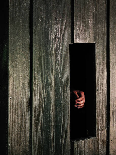 istock Cropped Hand Seen Through Broken Wooden Wall 1129723567