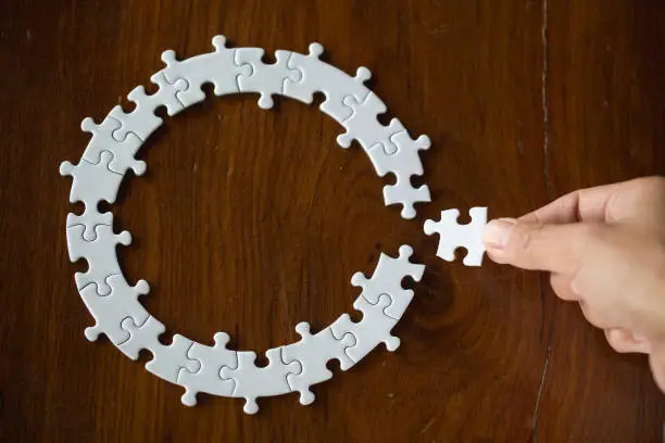 Photo of hand placing the last jigsaw puzzle piece,conceptual of problem solving