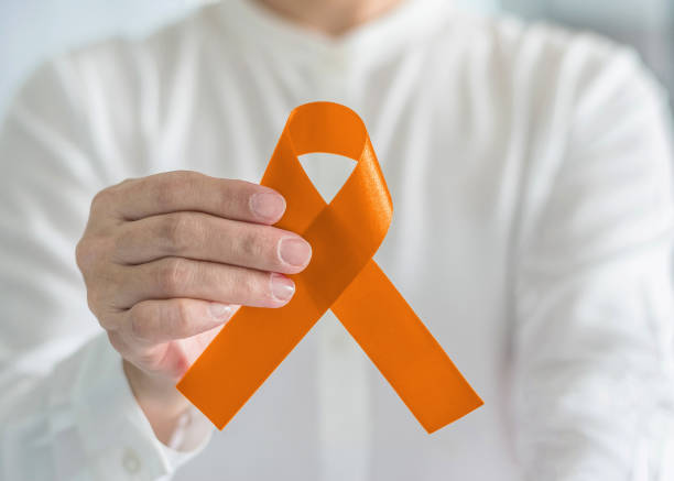 orange ribbon for awareness on leukemia, kidney cancer, rds disease, multiple sclerosis, adhd illness, chronic obstructive pulmonary disease (copd) in person's hand - kidney cancer imagens e fotografias de stock