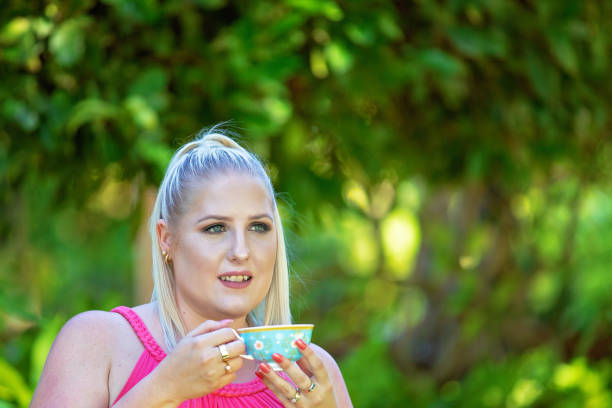 istock Pretty Young Woman Drinking Tea In The Garden 1129727429