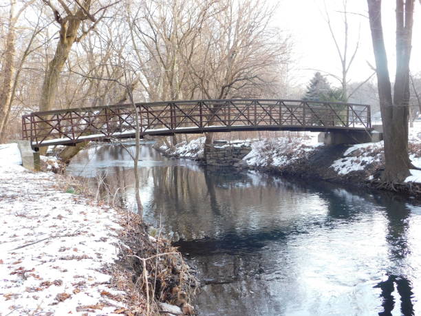 istock Metal footbridge over reflective stream and snow 1129732157