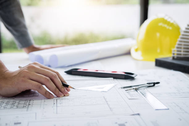 istock Cropped Hand With Blueprint In Office 1129732229