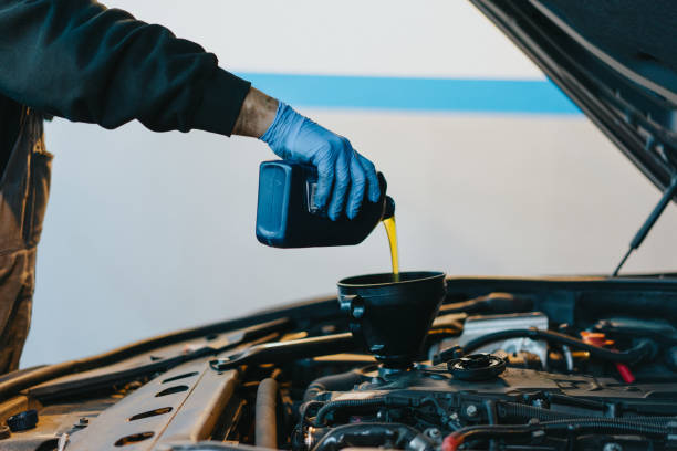 istock Cropped Hand Pouring Oil In Car Engine 1129733391