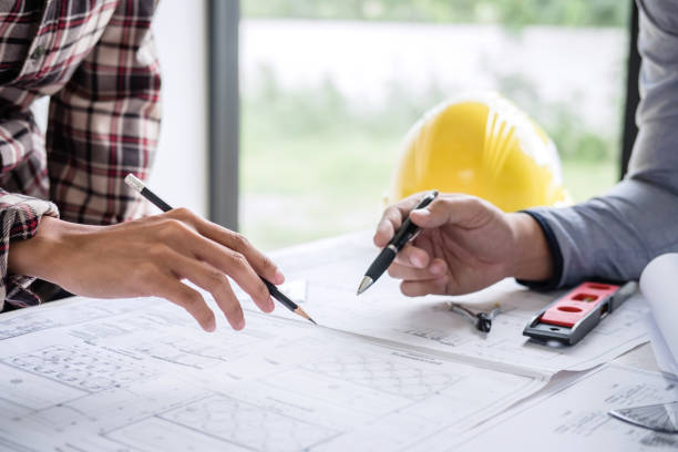 istock Architects Discussing Over Blueprint At Desk In Office 1129733515