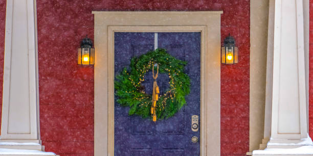 istock Blue door with wreath seen through falling snow 1129741573